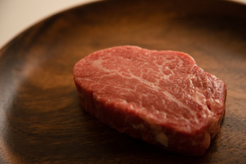 Raw Fillet Mignon Steak on the wooden round plate