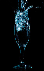 Splashes and drops of water in a glass are isolated on a black background.