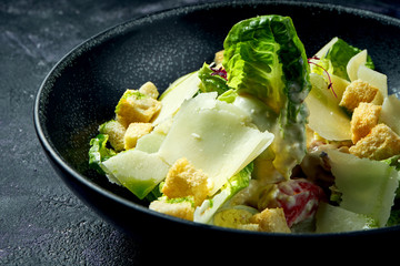 Classic Caesar salad with croutons, parmesan and white sauce in a ceramic bowl.. Close up
