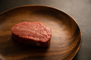 Raw Fillet Mignon Steak on the wooden round plate