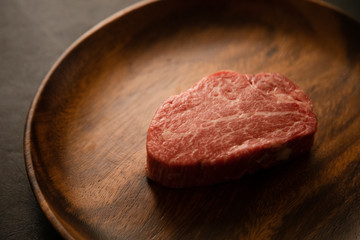Raw Fillet Mignon Steak on the wooden round plate
