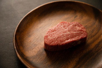 Raw Fillet Mignon Steak on the wooden round plate