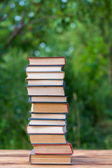 Stack of books on wooden table over nature background, outdoors