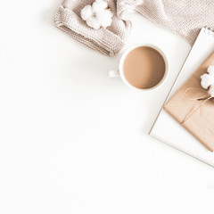 Autumn or winter composition. Cup of coffee, gift, dried autumn leaves, beige sweater on white background. Flat lay, top view