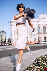 Stylish woman dancing on the edge in city