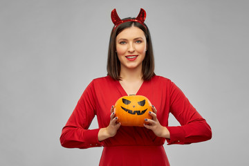 holiday, theme party and people concept - happy smiling woman in red halloween costume of devil...