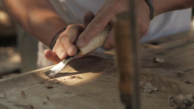 woodcarver processes a walnut wood board with a chisel. artisan makes a tea tray