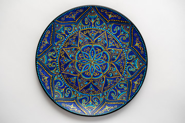 Decorative ceramic plate with black, blue and golden colors, painted plate on white background, dot...