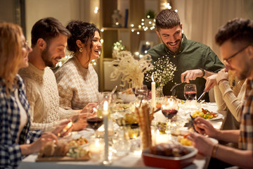 holidays, celebration and people concept - happy smiling friends having christmas dinner party at...