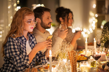 holidays and people concept - woman with smartphone at dinner party with friends at home
