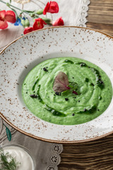 summer healthy green spinach soup on white plate on wooden table