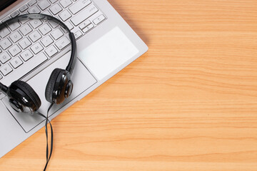 Headphones and laptop on wooden background.