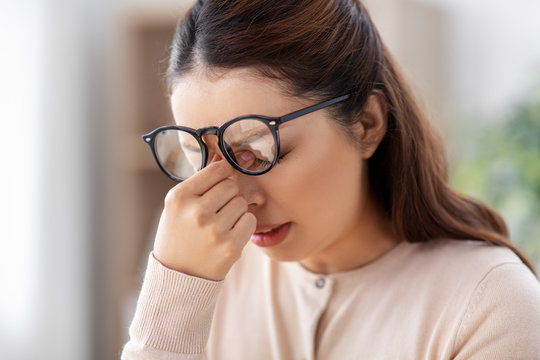 vision, stress and people concept - close up of tired asian woman with glasses rubbing her nose bridge