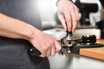 Barista makes coffee and holds a porta filter in her hands and presses coffee.