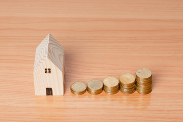 Money coin saving with a wooden home model on a wooden background.