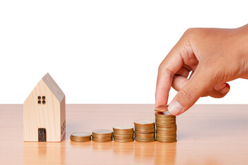 saving money hand putting coins with wooden home model on white background.