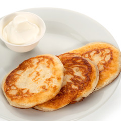 Three pancakes on a plate and a little sour cream on a white background. Full depth of field. With clipping path.