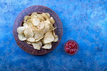 Potato chips on a plate. Wooden table. Salty food for beer