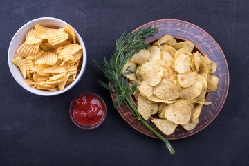 Potato chips on a plate. Wooden table. Salty food for beer