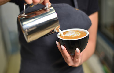 Barista guy makes coffee and pours it into a mug. Small business and addiction concept