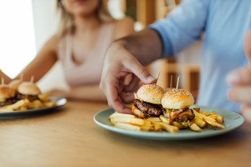 Eating mini burgers with friends, close-up.