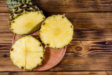 Cutting board with sliced pineapple on wooden table. Top view