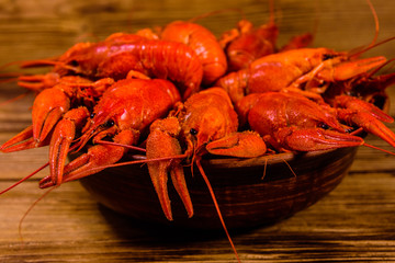 Plate with boiled crayfishes on wooden table