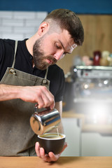 Barista guy makes coffee and pours it into a mug. Small business and addiction concept