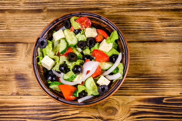 Ceramic plate with greek salad on wooden table. Top view