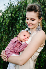 The mother holds little newborn girl on nature, outdoors. Portrait of mom and daughter. The concept of family holiday. upper half. Close up.