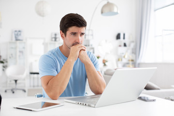Obraz na płótnie Canvas Sad man with a laptop at home. Freelance and selfemployment concept.