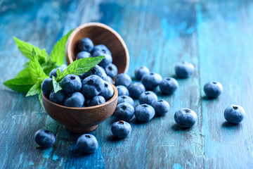 Bowl of fresh blueberries on blue rustic wooden table closeup. - Powered by Adobe