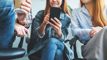 A group of young people looking at the same mobile phone while hanging together