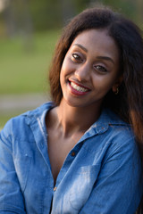 Happy young beautiful African woman at the park outdoors