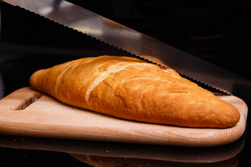 Homemade white bread is cut with a large knife. Baking at home.