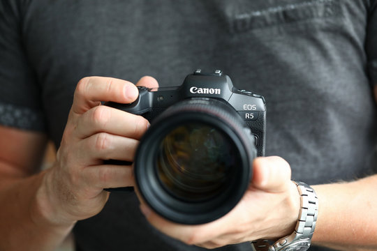 Male hand holding brand new mirrorless digital camera Canon r5 closeup