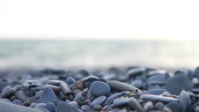 Pebbles on the beach with sea waves on the background