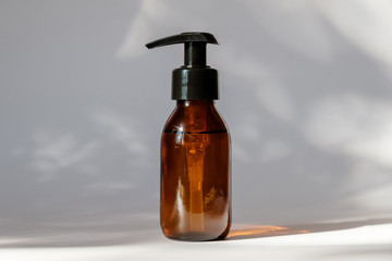 Brown amber glass bottle with lotion pump dispenser. Cosmetic container for shampoo, essential oil, lotion soap