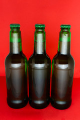 Vertical image.Three bottles of beer on the red background.Roduct presentation