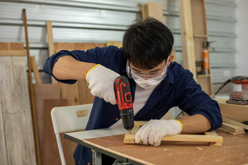 Asian man Carpenter working with technical drawing or blueprint construction paper lying on a workshop with carpentry tools and wood at home