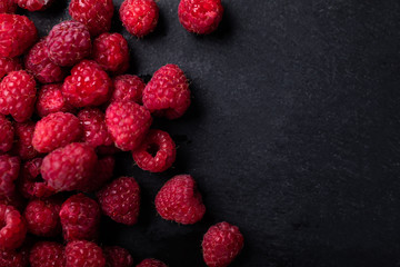 Raspberries on a black stony background, top view with a copy-space.