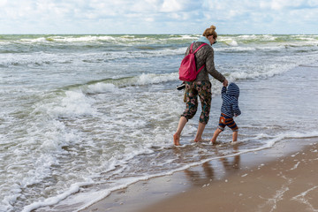 Young woman and little boy enjoy beautiful view of Baltic sea. .Windy summer day. Vacation and lifestyle concept.