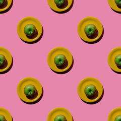 Fresh green apple on yellow saucer on pink background. Seamless pattern. Top view. Flatly. Hard light.