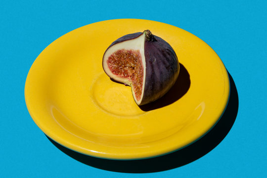 Fresh fig on yellow saucer on blue background, styled photo. High resolution.