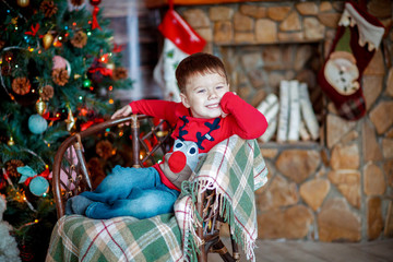 little boy sitting near chrismas tree