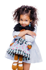 Portrait of a cute little african american girl hugging doll, isolated on white background