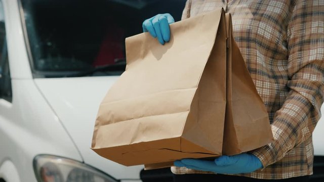 Messenger transfers bags of groceries to the recipient near the delivery service van