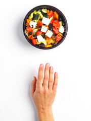 The woman's hand reaches for fresh salad. Look from above