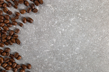Coffee beans are scattered on a stone table, background. Copy space.