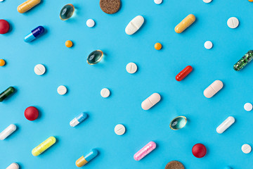 Creative layout of pills and capsules on blue background with summer sun and sharp shadow. Covid-19 or Coronavirus minimal art concept.